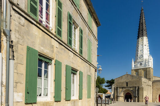 Historische Kirche mit spitzem Glockenturm und traditionellen H�usern in Ars-en-R�.