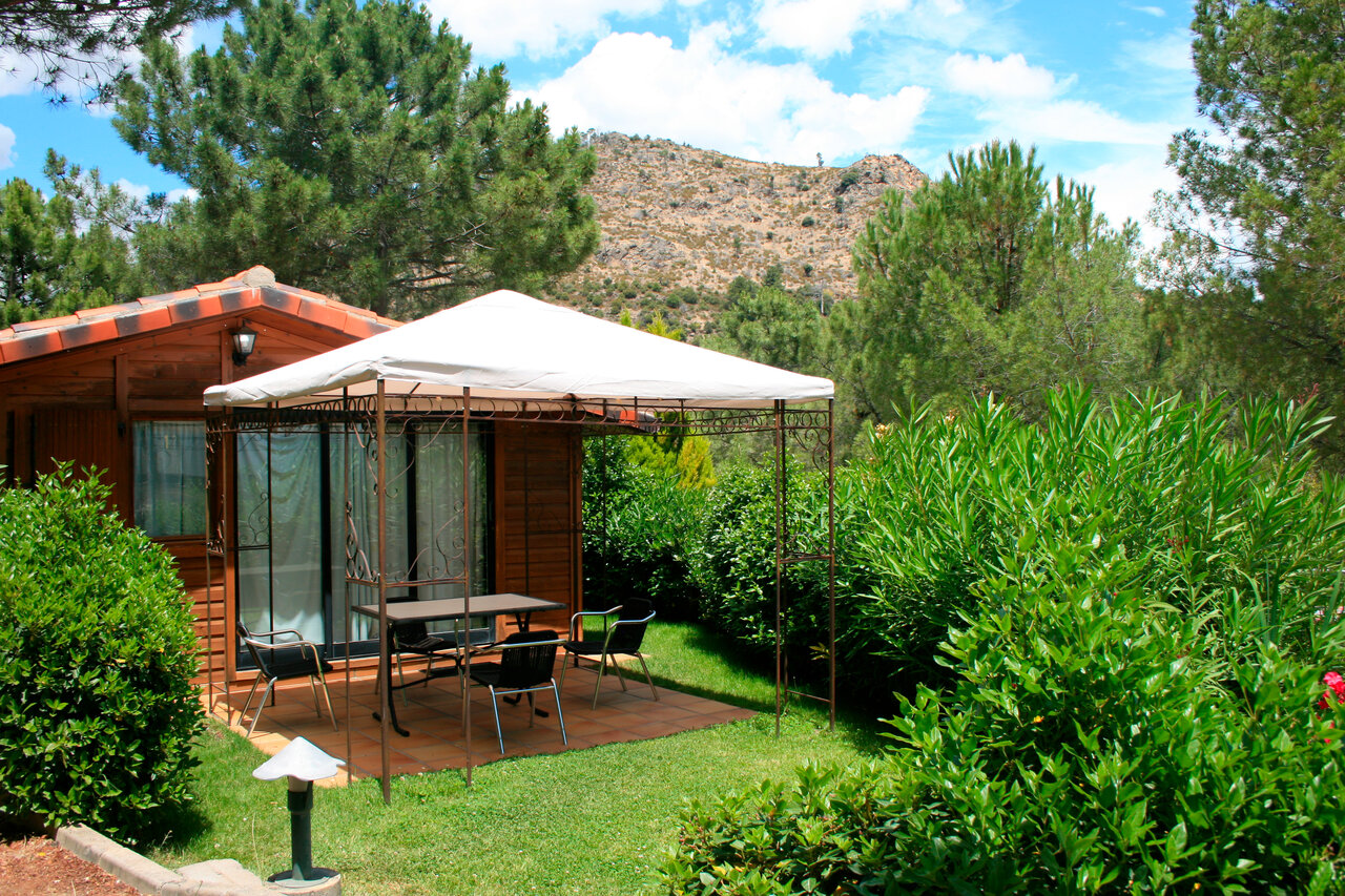 Chalet madera, terraza sombreada y vegetaci�n en el camping CAPFUN El Canto La Gallina en Valdemaqueda (Madrid).