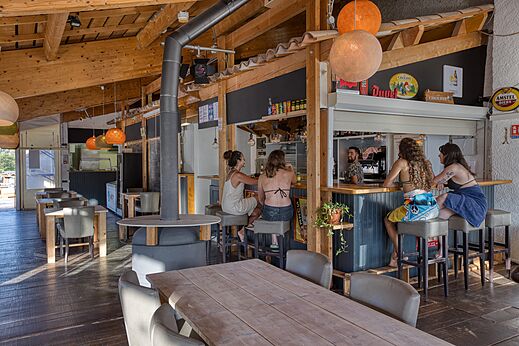 Holzbar und Restaurant mit Gästen auf dem Campingplatz CLICOCHIC Castillon de Provence in Castellane (04).