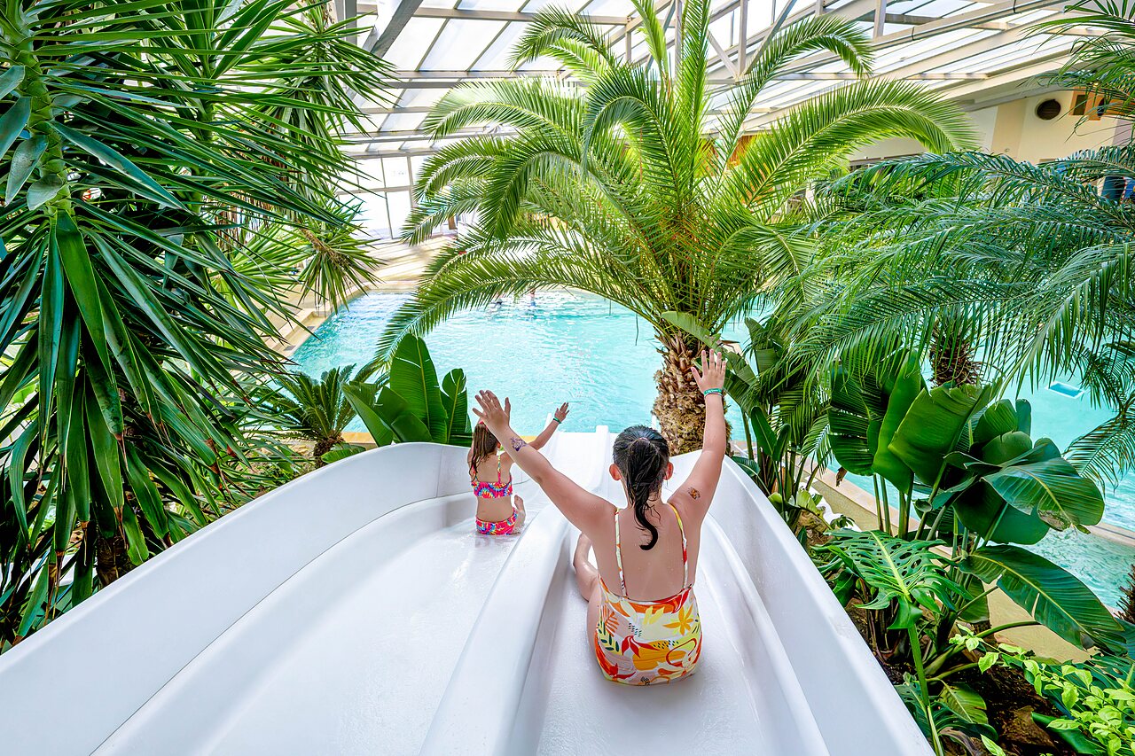 Waterglijbaan en overdekt zwembad met kinderen op camping CAPFUN Cenic in PENESTIN (56).