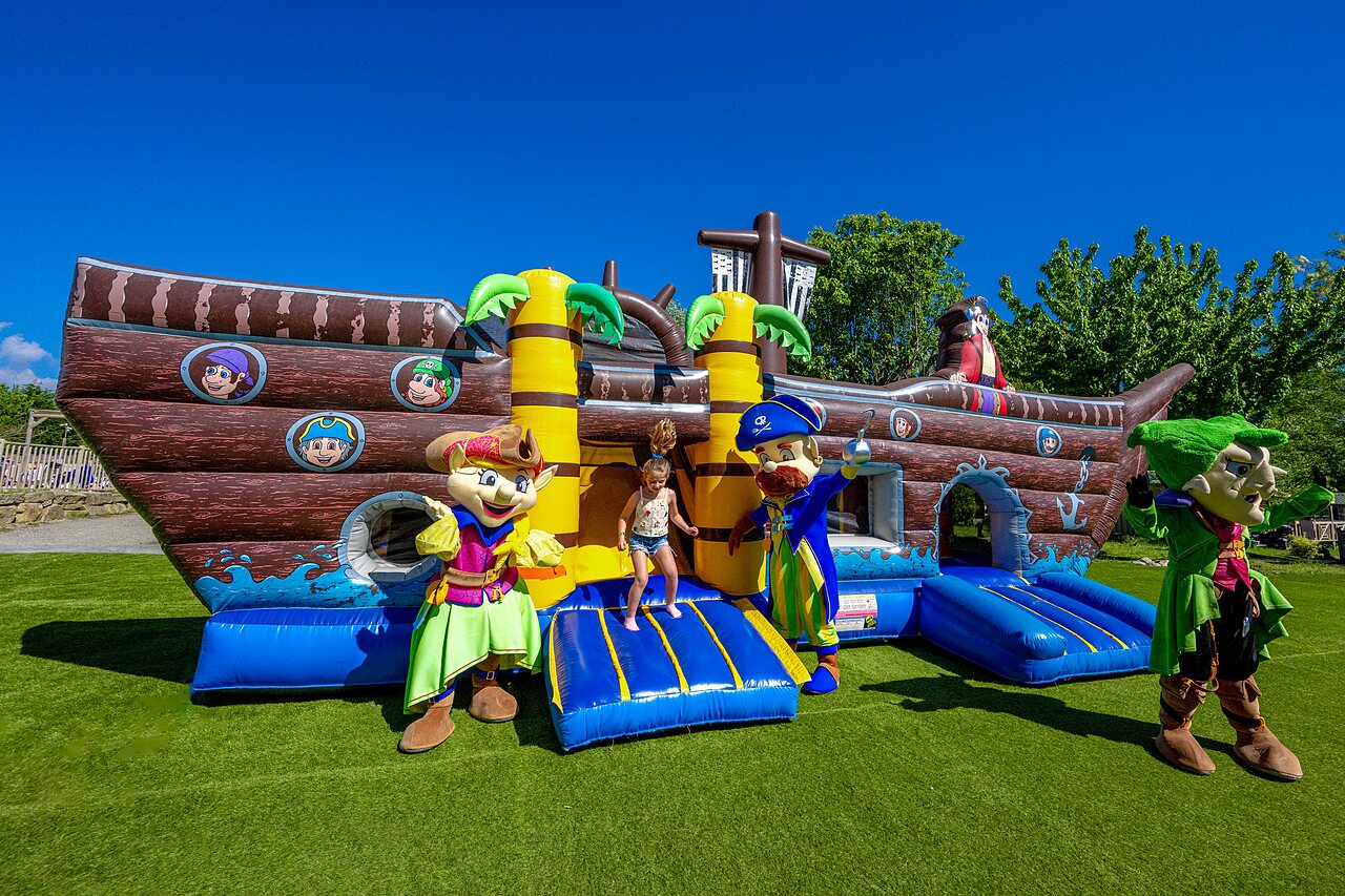 Opblaasbaar piratenschip kasteel met mascottes en kind op camping CAPFUN Cenic in PENESTIN (56).