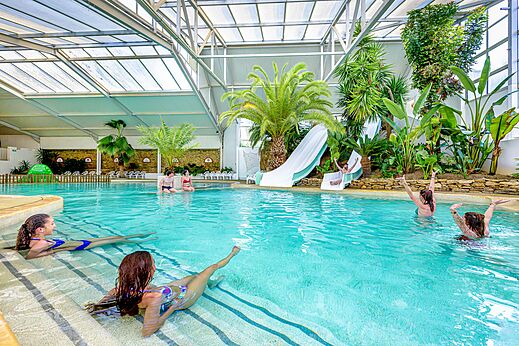 �berdachtes Schwimmbad mit Rutschen und tropischen Pflanzen auf Camping CAPFUN Cenic in PENESTIN (56).