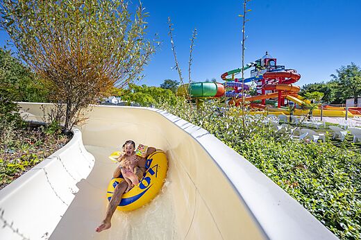Kind und Erwachsener auf Reifen Wasserrutsche auf Camping CAPFUN Cenic in PENESTIN (56).