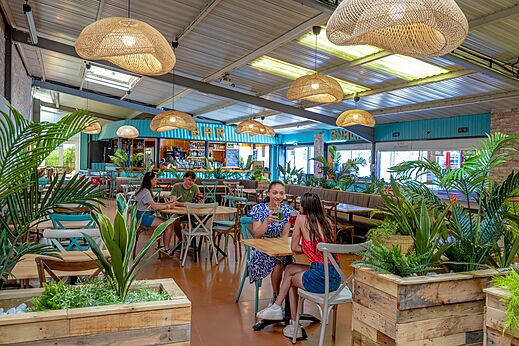 Moderner Bar- und Restaurantbereich mit Gästen auf Campingplatz CAPFUN Cenic in PENESTIN (56).