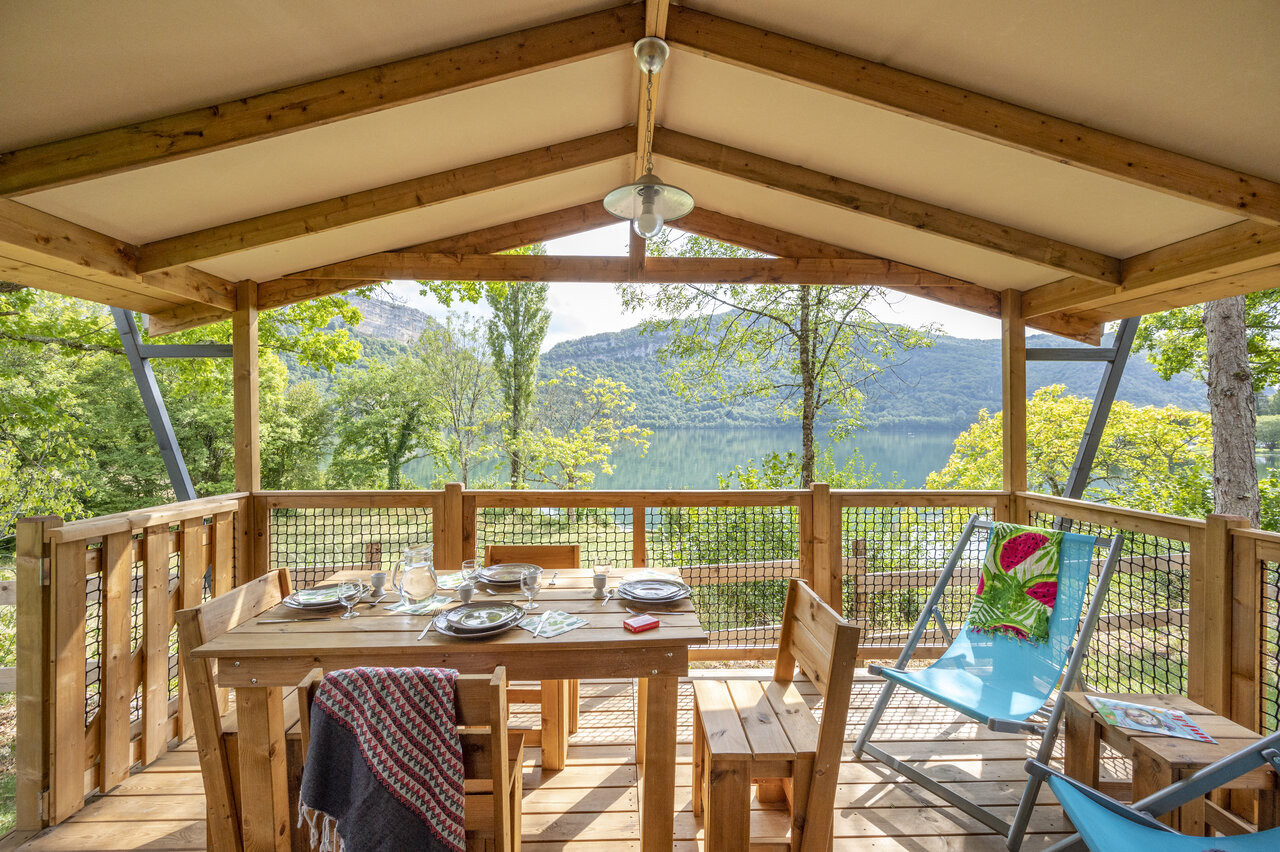 Covered accommodation terrace with table and lake view at CLICOCHIC Chancia (01).