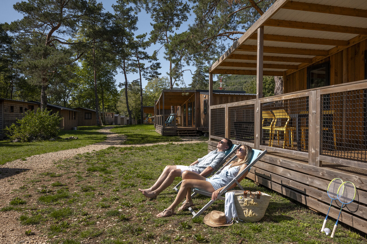 Couple relaxing by mobile home with terrace, CLICOCHIC Chancia campsite (01).