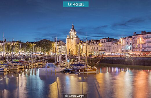 Beleuchteter Alter Hafen von La Rochelle mit dem Uhrturm und Booten.