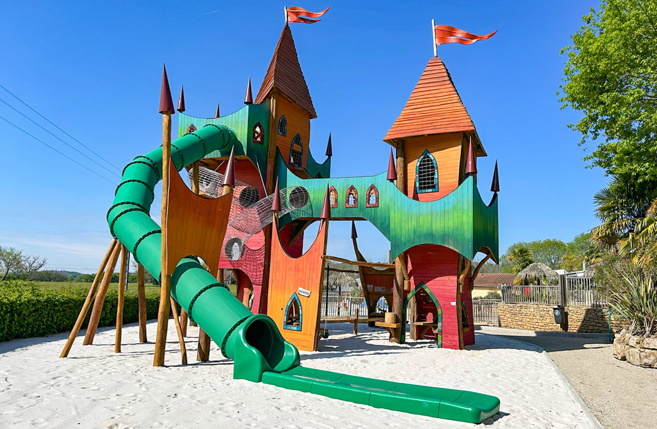 Large castle playground structure with slide at VAGUES OCEANES Chataigneraie campsite in Prats-de-Carlux (24).