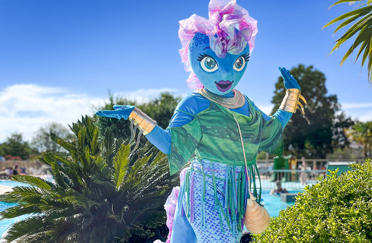 Blue mermaid mascot animating the outdoor swimming pool at VAGUES OCEANES Chataigneraie campsite in Prats-de-Carlux.