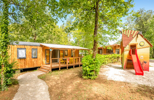 Wooden Mobil-home, terrace, children's games at VAGUES OCEANES Chataigneraie campsite.