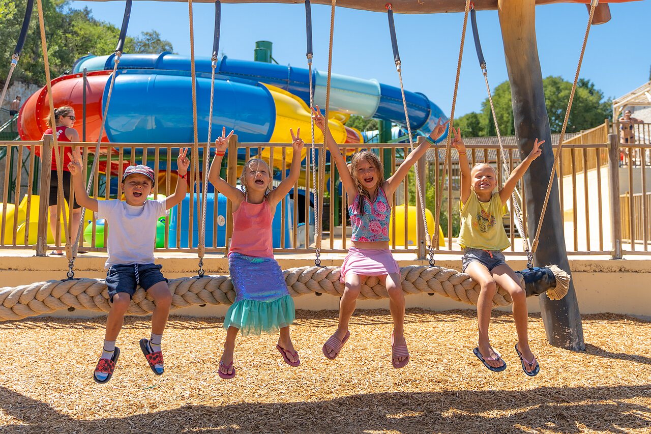 Enfants souriants sur balan�oire, toboggans aquatiques au camping CLICOCHIC Ch�teau de Boisson (30).