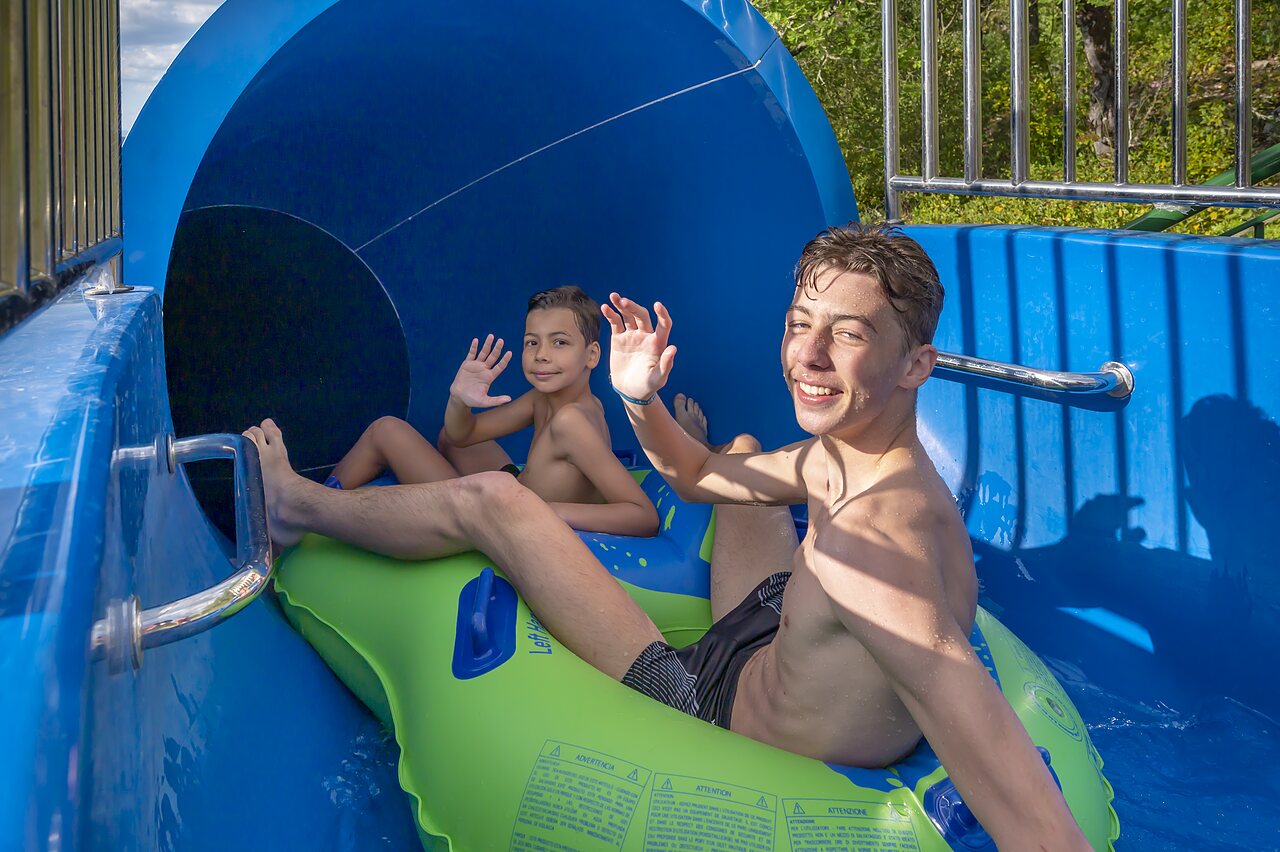 Toboggan aquatique avec enfants souriants sur bou�e au camping CLICOCHIC Ch�teau de Boisson � All�gre-les-Fumades (30).