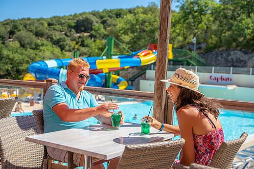 Couple au bar, vue sur l'espace aquatique, au camping CLICOCHIC Ch�teau de Boisson � All�gre-les-Fumades (30).