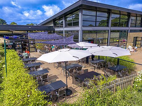 Außenterrasse des Restaurants mit Tischen und Sonnenschirmen auf dem Campingplatz CAPFUN Château de Galinée.