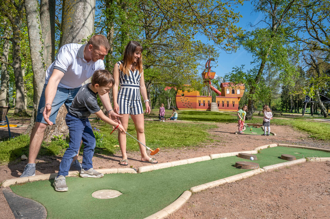 Famille jouant au mini-golf avec aire de jeux au camping CAPFUN Chateau d'Arvid � Villerville (14).