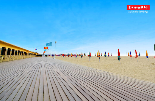 Strandpromenade von Deauville mit Strandkabinen und bunten Sonnenschirmen in der Normandie.