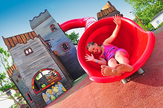 Happy child on red slide of playground at CAPFUN Chênes campsite in Medis/Royan (17).