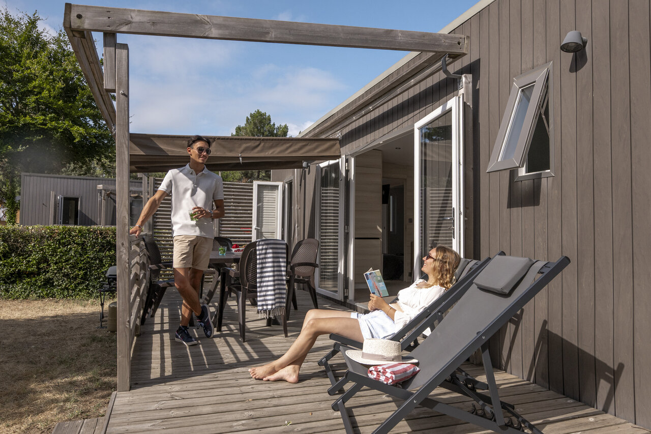 Modernes Mobilheim mit Terrasse, Paar entspannt auf Camping CLICOCHIC Chouans in SAINT HILAIRE DE RIEZ.