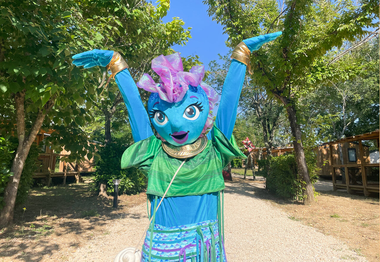 Blue and green mascot entertaining on the paths of VAGUES OCEANES Les Cigales campsite in Moliets-Plage (40).