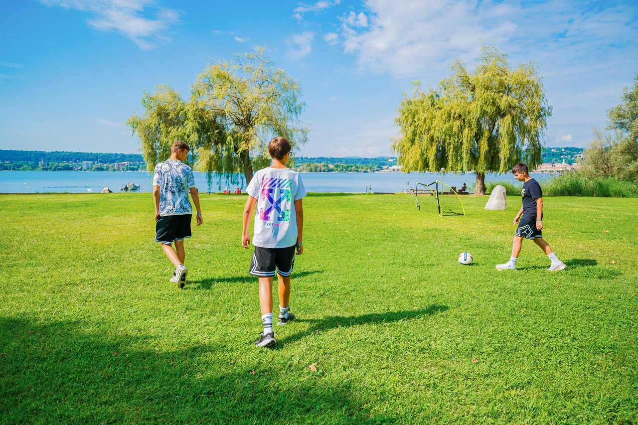 Jungen spielen Fu�ball auf Rasen, See, CAPFUN Citta di Angera in Angera VA.