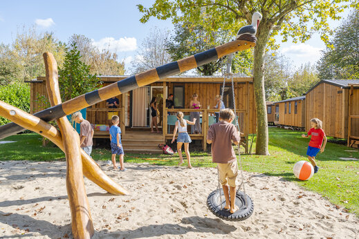 Aire de jeux avec balançoire et enfants devant des Mobil-homes au camping CAPFUN Citta di Angera à Angera VA (21).
