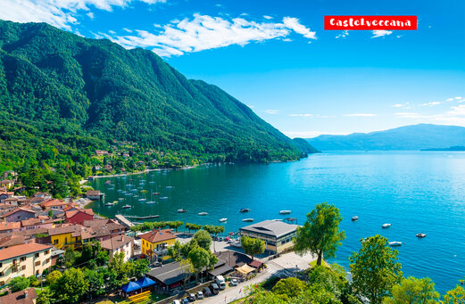 Village de Castelveccana au bord du lac Majeur, entouré de montagnes verdoyantes.
