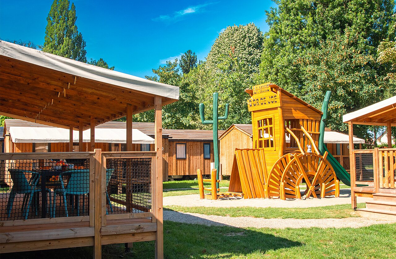 Western-Spielplatz und Unterkunftsterrasse auf dem Campingplatz CLICOCHIC in Gerstheim (67).