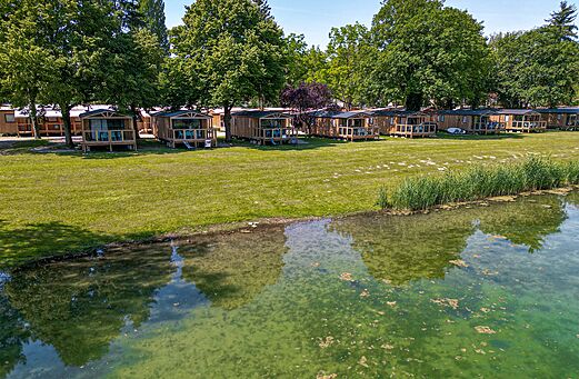 Mobil-homes en bois avec terrasses au bord de l'eau au camping CLICOCHIC.
