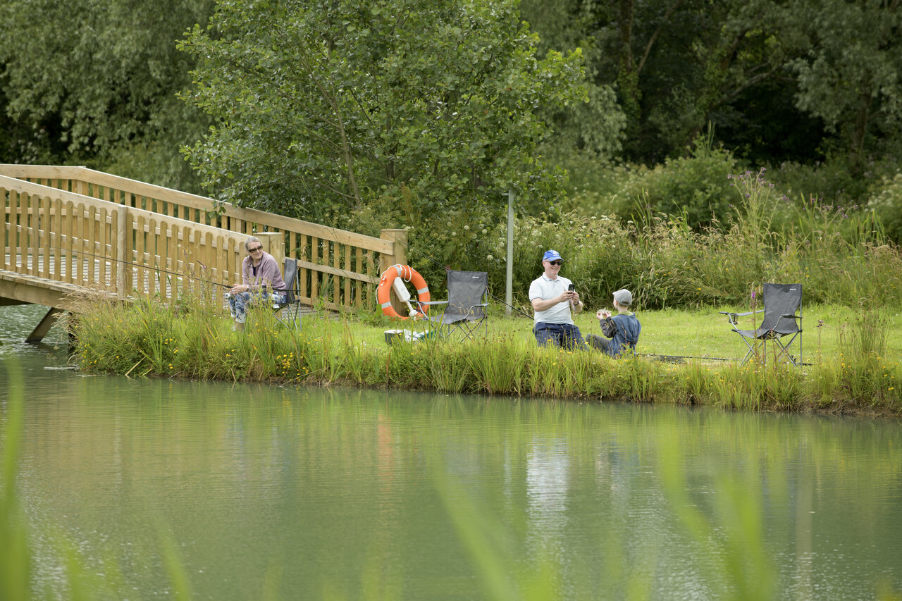 Pesca familiar junto al lago, puente de madera en el camping CAPFUN UK Clawford Lakes en Clawton, Holsworthy.