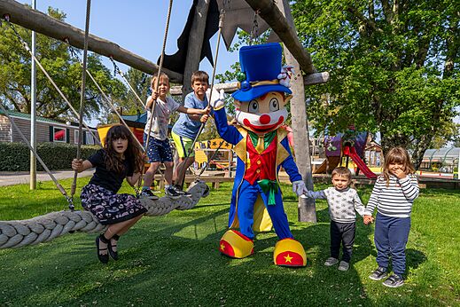 Maskottchen und Kinder spielen auf dem Spielplatz auf dem Campingplatz CAPFUN Clown Océan in TOSSE (40).
