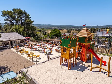 Castle playground and outdoor restaurant terrace at CLICOCHIC Commanderie campsite in Rustiques (11).