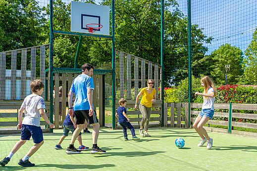 Famille jouant au football sur terrain multisport au camping CAPFUN Coquelicots � Royan (17).