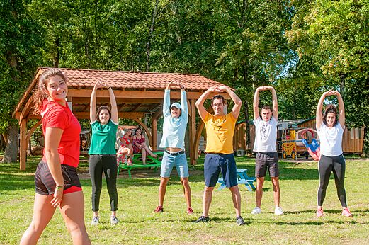 Groupe d'adultes faisant des �tirements en plein air au camping CAPFUN Coquelicots � Royan (17).