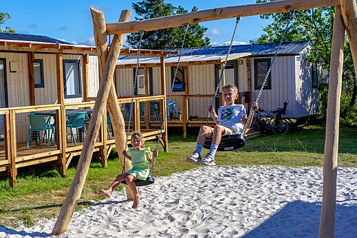 Kinder spielen auf Schaukeln, Mobilheime auf dem Campingplatz VAGUES OCEANES Coq Hardi.