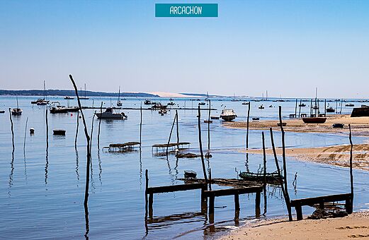 Bucht von Arcachon mit Booten und der Dune du Pilat im Hintergrund.