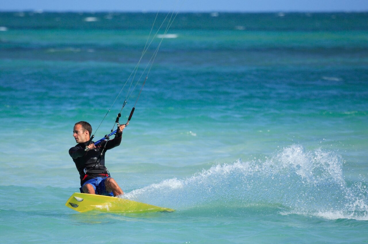 Mann beim Kitesurfen auf t�rkisfarbenem Wasser, dynamische Spritzer auf dem Campingplatz CAPFUN C�te Vermeille : Cabane dans les airs � Port La Nouvelle (11).