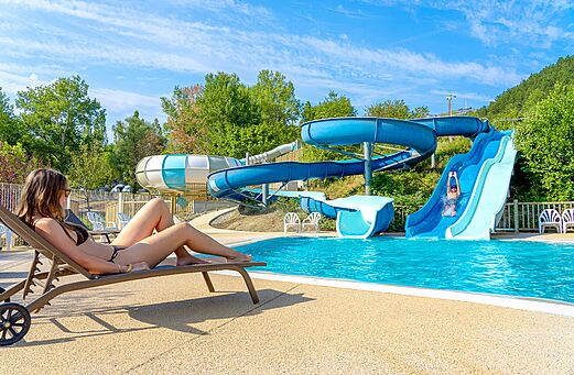 Piscine extérieure, toboggans aquatiques et chaises au camping CLICOCHIC Couriou.