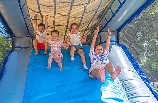 Kinder spielen auf einer aufblasbaren Rutsche auf dem Campingplatz CLICOCHIC Couriou in Recoubeau-Jansac.
