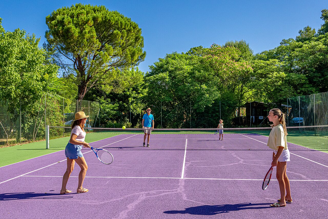 Familie spielt Tennis auf lila Platz auf dem Campingplatz CLICOCHIC Couteli�re in Lagnes (84).