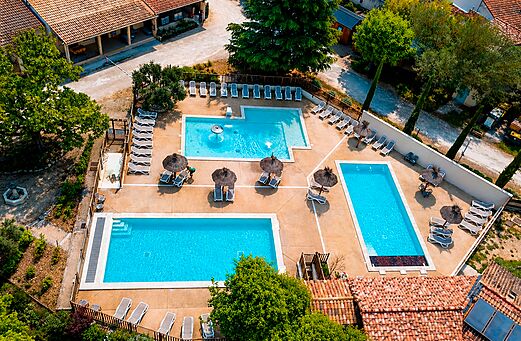 Luftaufnahme mehrerer Pools mit Stühlen auf dem Campingplatz CLICOCHIC Coutelière in Lagnes (84).
