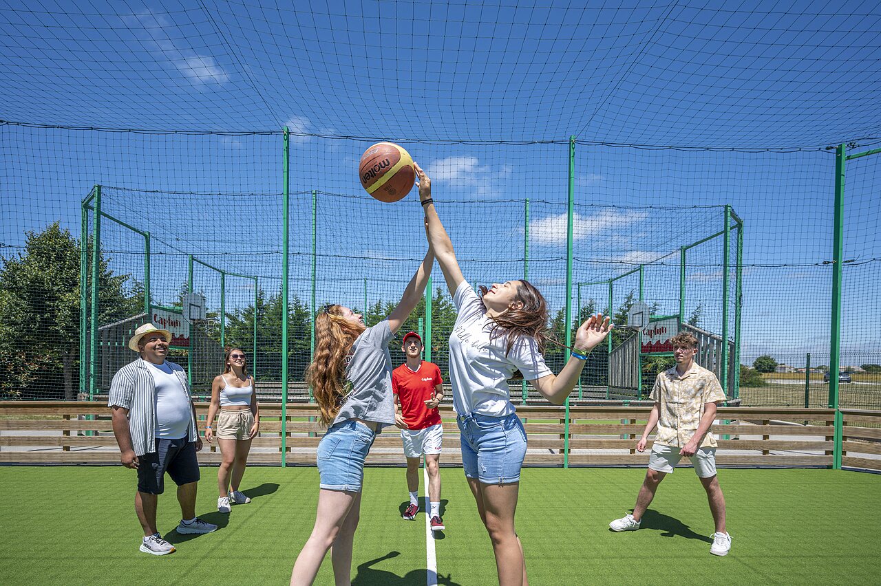 Zwei junge Frauen spielen Basketball auf Multisportplatz auf Camping CAPFUN Curty's in Jard sur Mer (85).