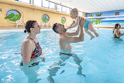 Famille avec b�b� jouant dans la piscine int�rieure au camping CAPFUN Curty's � Jard sur Mer (85).