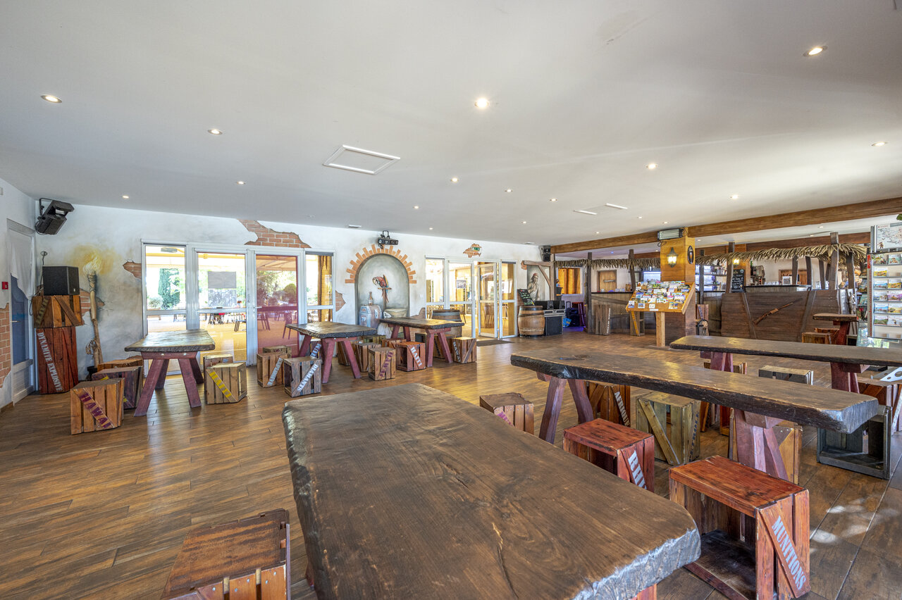 Thematische Bar und Restaurant mit gro�en Holztischen auf dem Campingplatz CAPFUN Dauphins Bleus in GIVRAND (85).