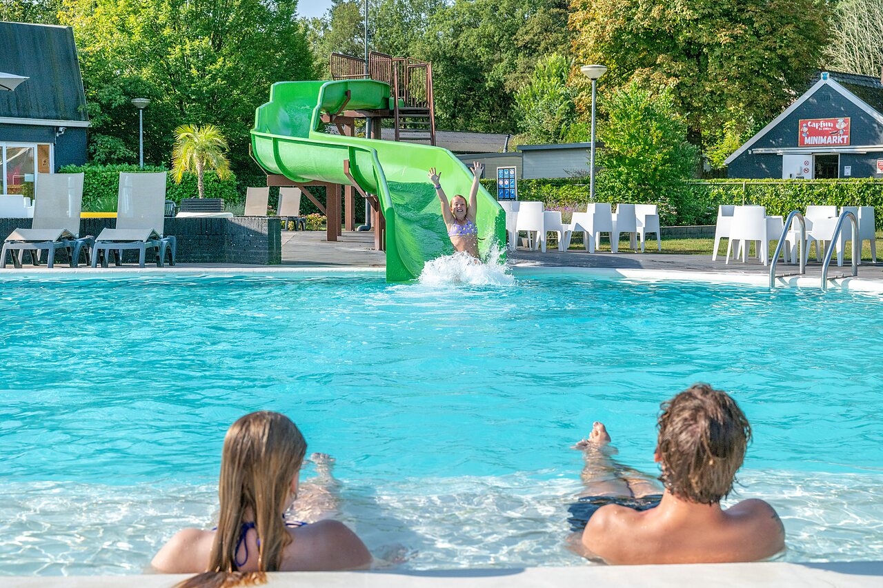 Wasserrutsche und Au�enpool mit spielenden Kindern auf dem Campingplatz CAPFUN De Belten in Rheeze.