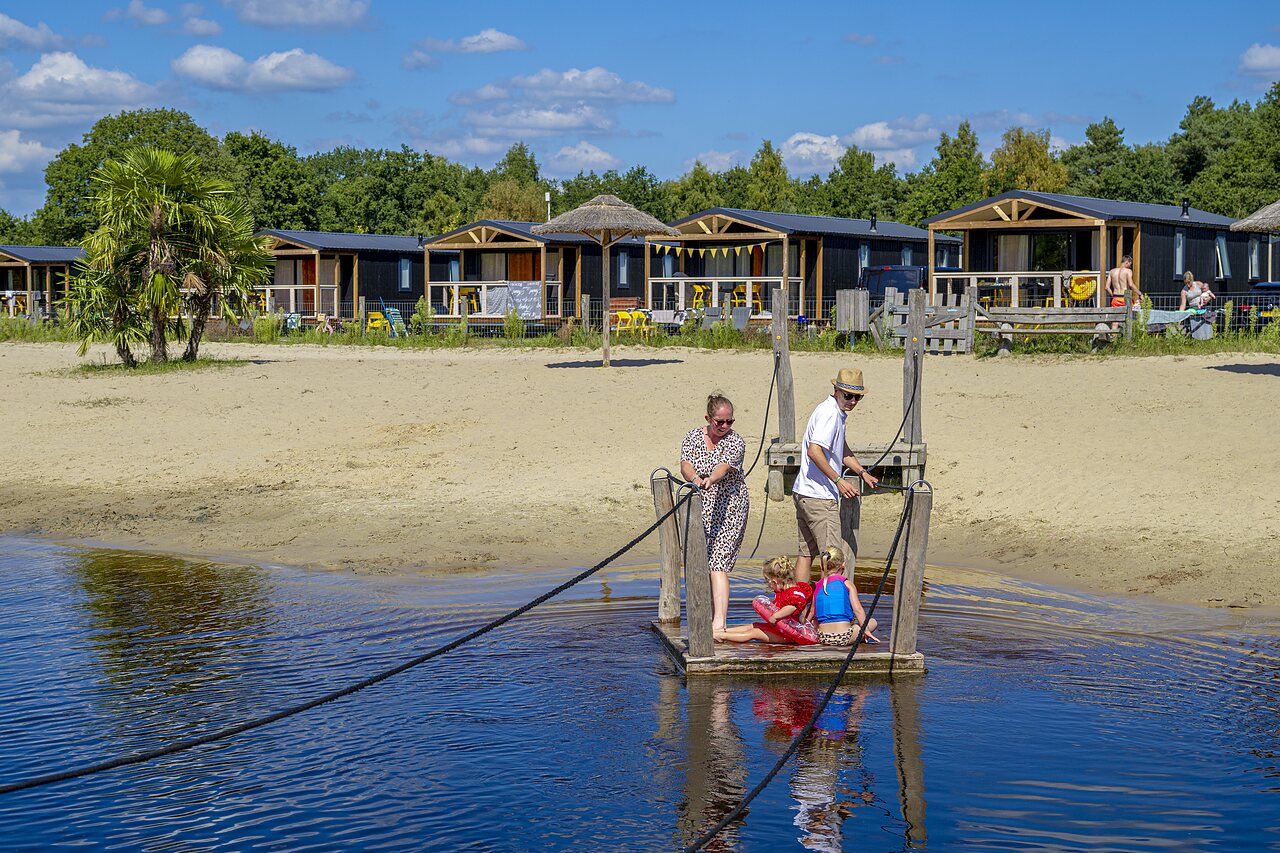 Familie auf Flo�, Sandstrand und Unterk�nfte auf dem Campingplatz CAPFUN De Belten in Rheeze.