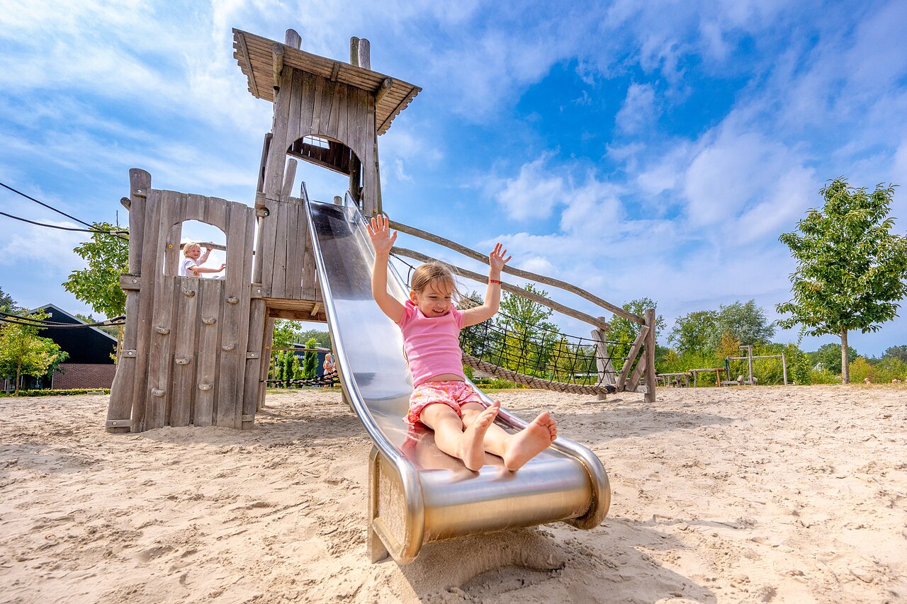 Kinder spielen auf Rutsche und Holzspielturm im Camping CAPFUN De Belten in Rheeze.
