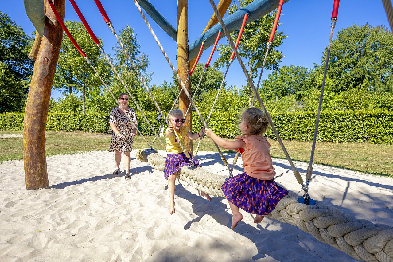 Zwei Kinder spielen auf einer riesigen Seilschaukel auf dem Campingplatz CAPFUN De Belten in Rheeze.
