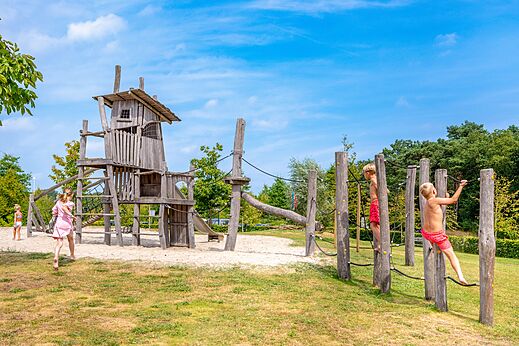 Großer Holzspielplatz mit kletternden Kindern auf dem Campingplatz CAPFUN De Belten in Rheeze.