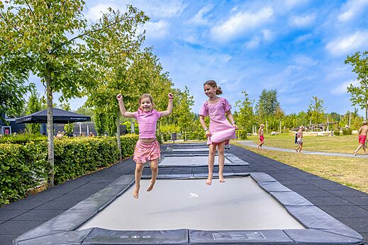 Zwei Mädchen springen auf Trampolinen auf dem Campingplatz CAPFUN De Belten in Rheeze.