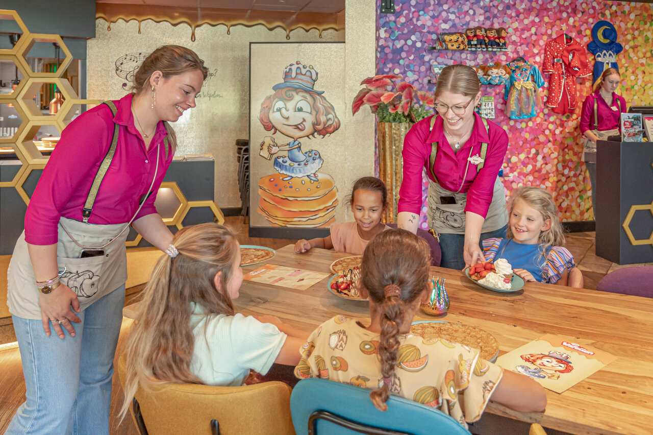 L�chelndes Personal serviert Kindern Pfannkuchen im Restaurant CAPFUN De Bongerd Tuitjenhorn.